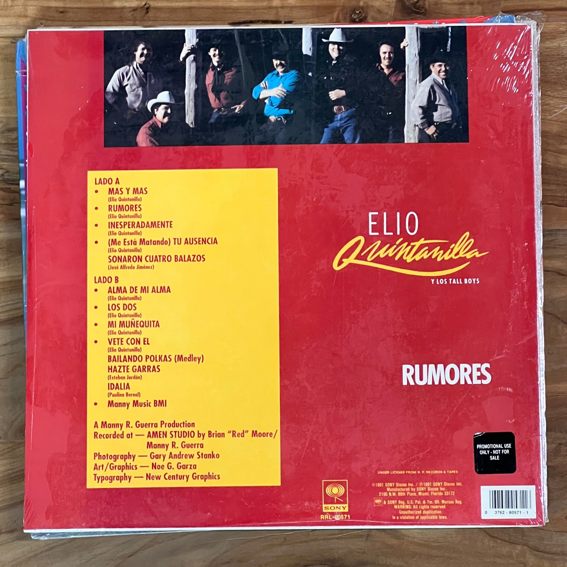Back cover of a music album with red and yellow design on a wooden surface